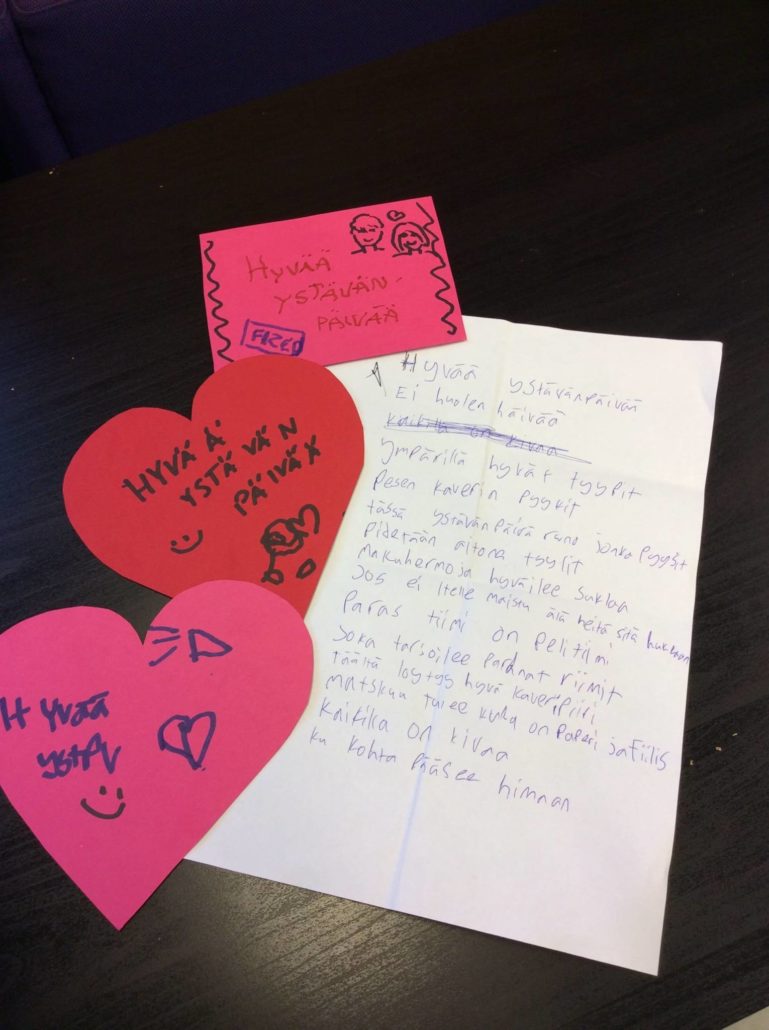 Sydämenmallisiin kortteihin kirjoitettu hyvää ystävänpäivää. Lisäksi paperi, jossa ystävänpäiväruno.